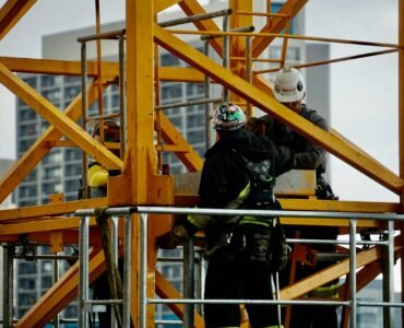 man in black jacket and helmet climbing orange ladder